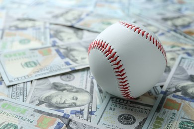 Photo of Baseball ball on many dollars bills, closeup