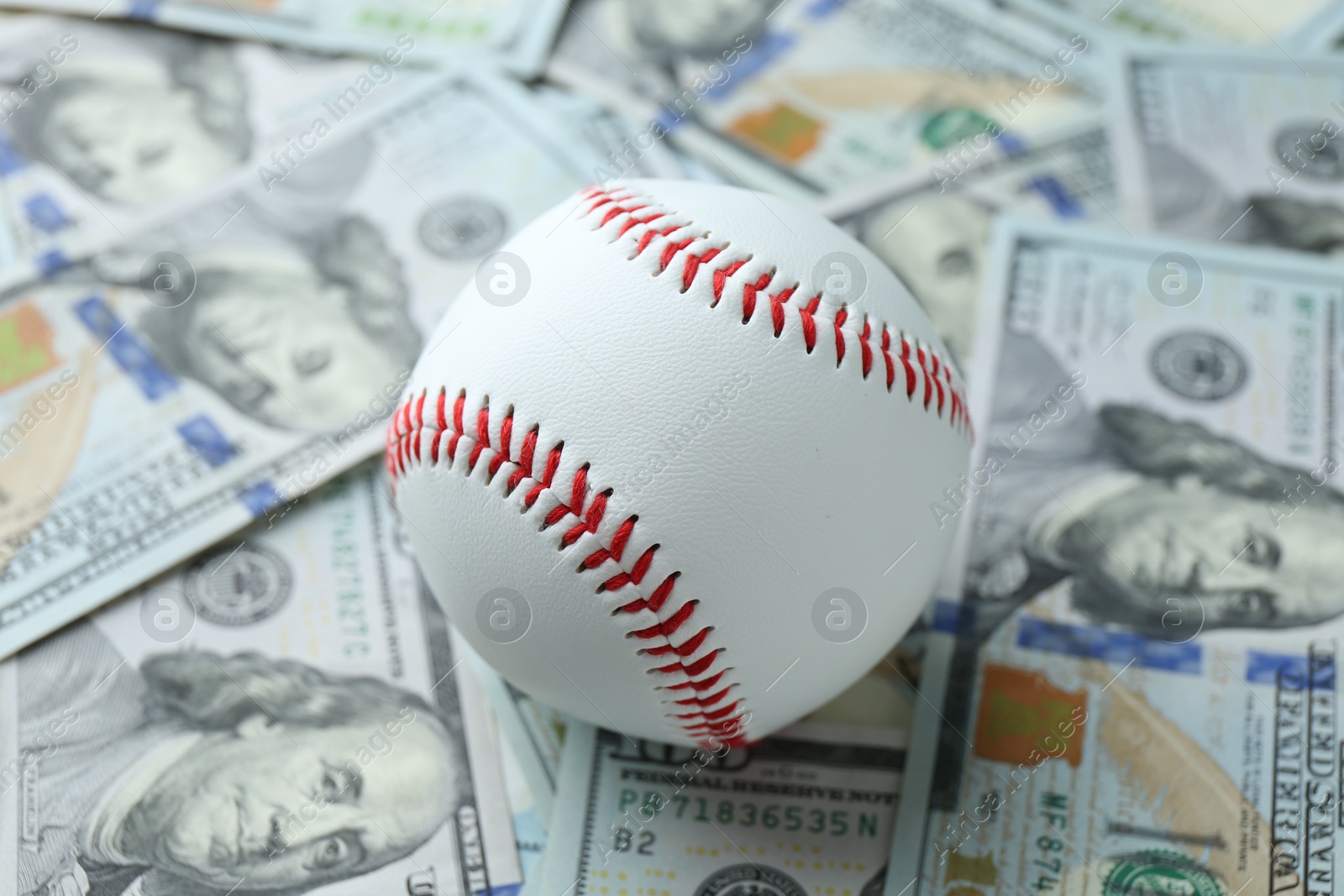 Photo of Baseball ball on many dollars bills, closeup