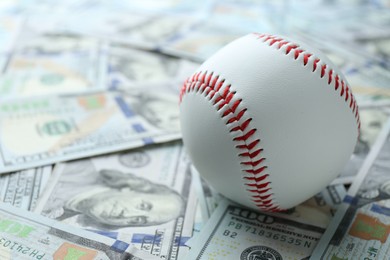 Photo of Baseball ball on many dollars bills, closeup