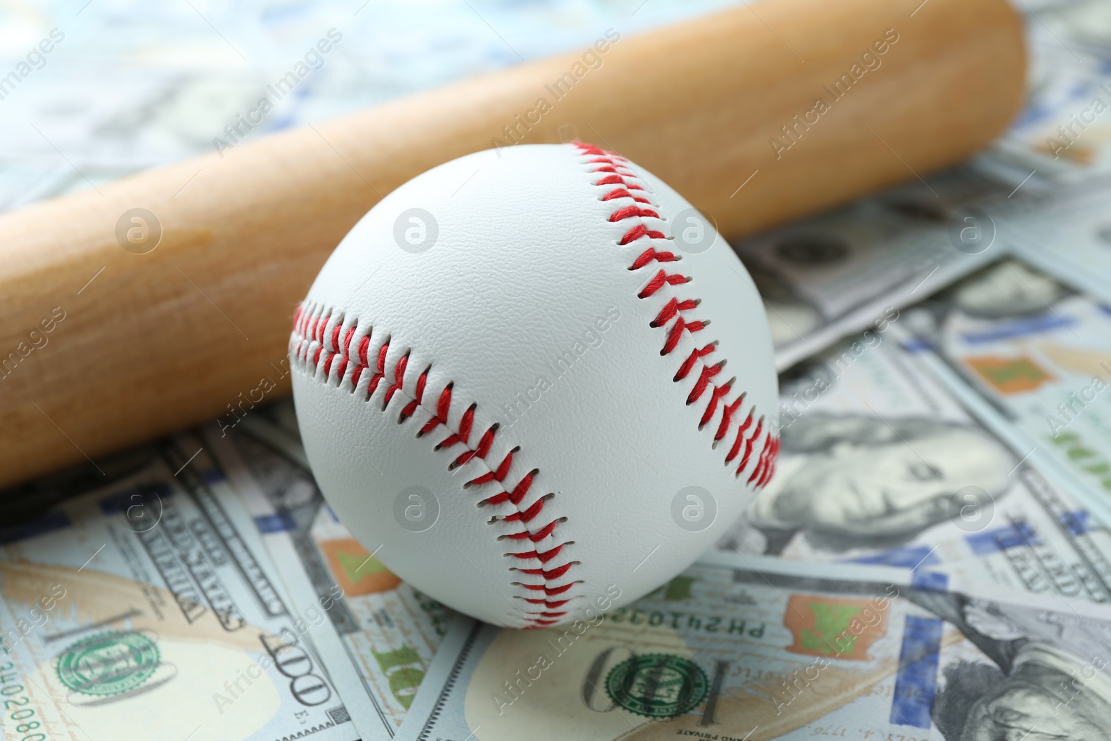 Photo of Baseball ball and bat on dollars bills, closeup