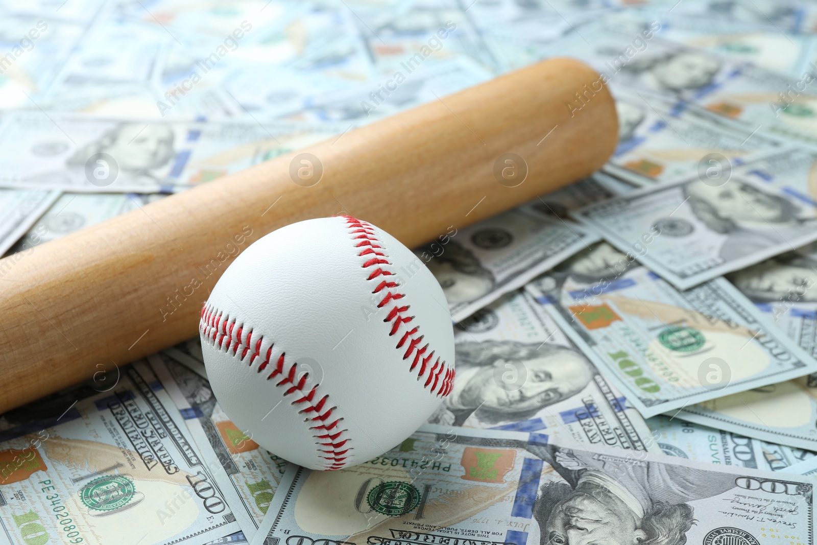 Photo of Baseball ball and bat on dollars bills, closeup