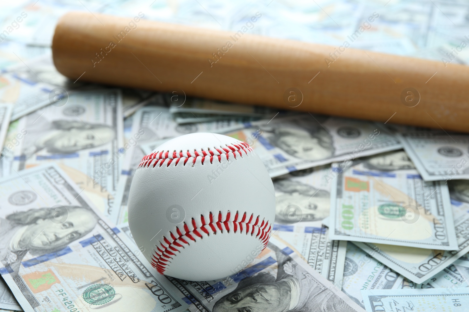 Photo of Baseball ball and bat on dollars bills, closeup