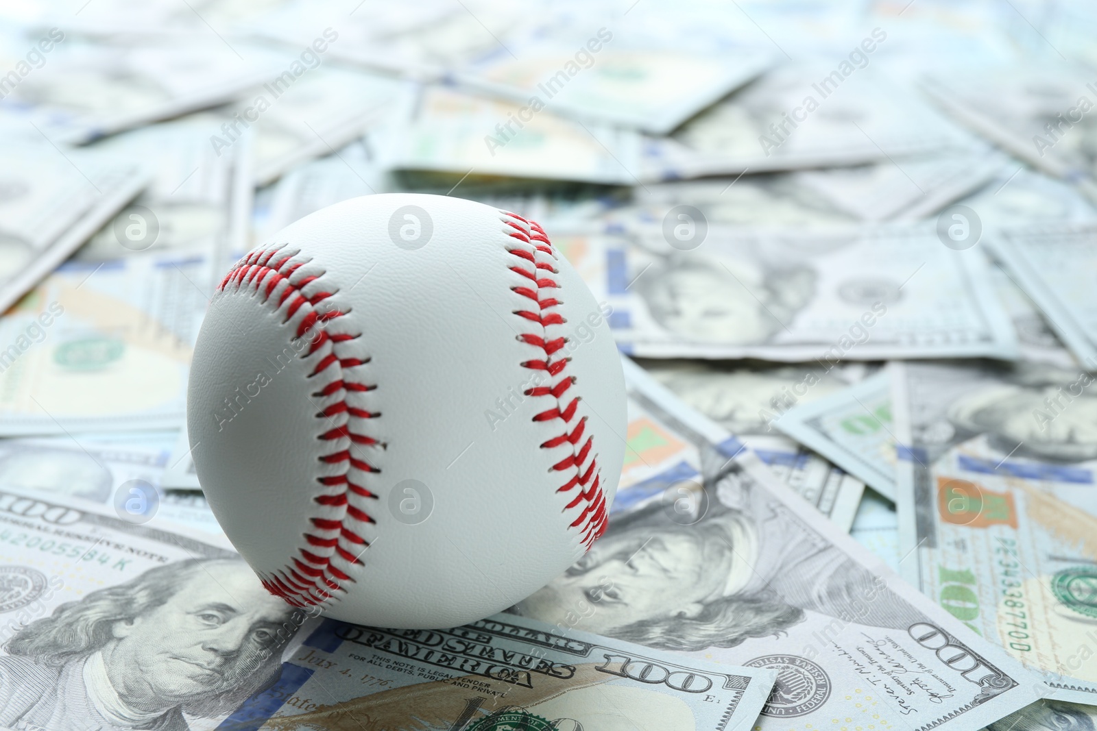 Photo of Baseball ball on many dollars bills, closeup