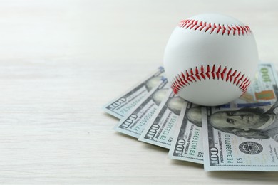 Photo of Baseball ball and dollar bills on white wooden table, closeup. Space for text