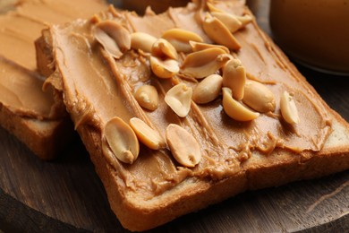 Delicious sandwiches with peanut butter and fresh nuts on wooden board, closeup