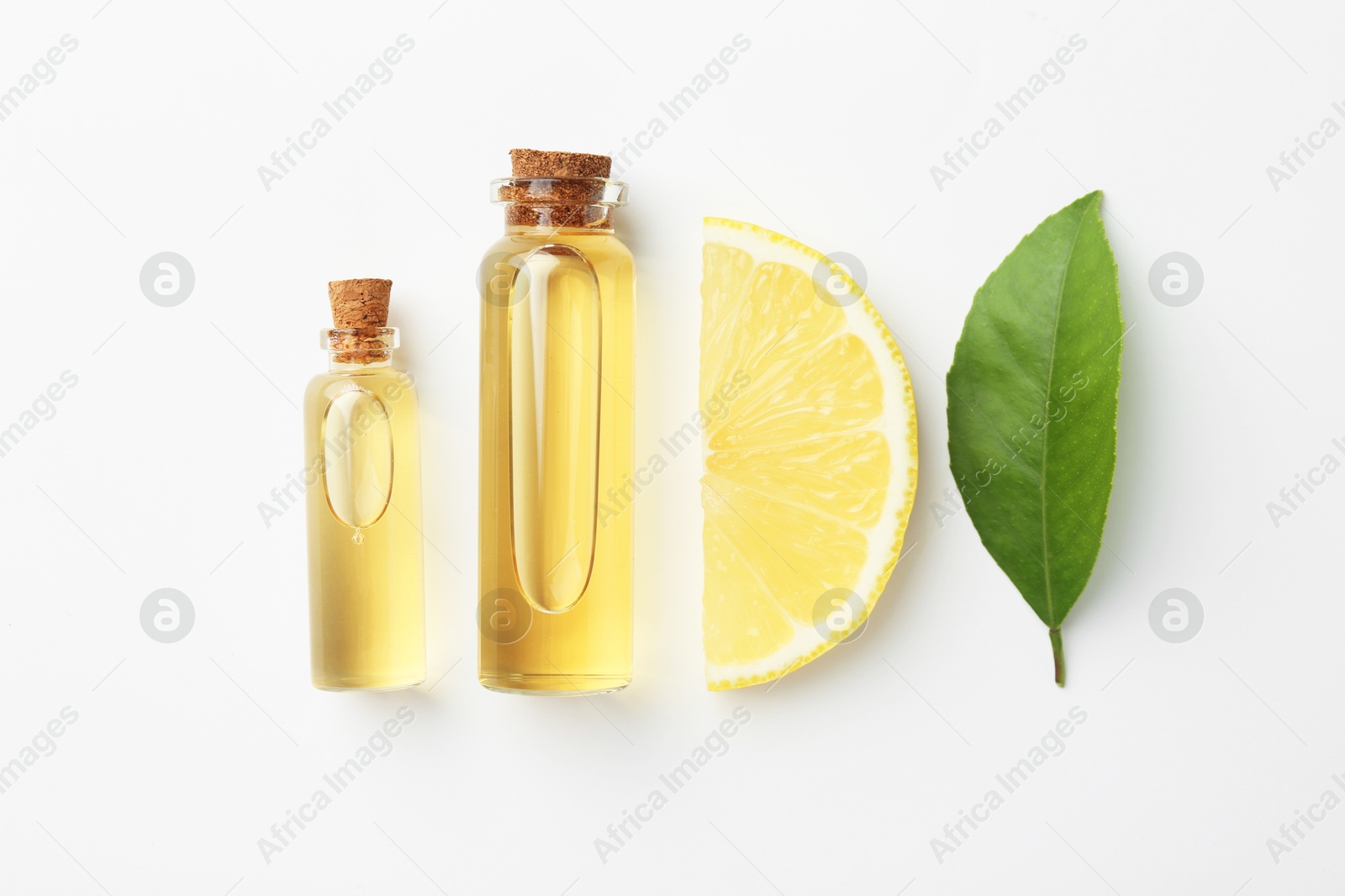 Photo of Bottles of essential oils, lemon and green leaf on white background, flat lay