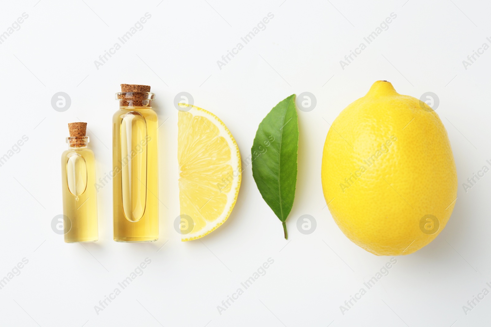 Photo of Bottles of essential oils, lemon and green leaf on white background, flat lay