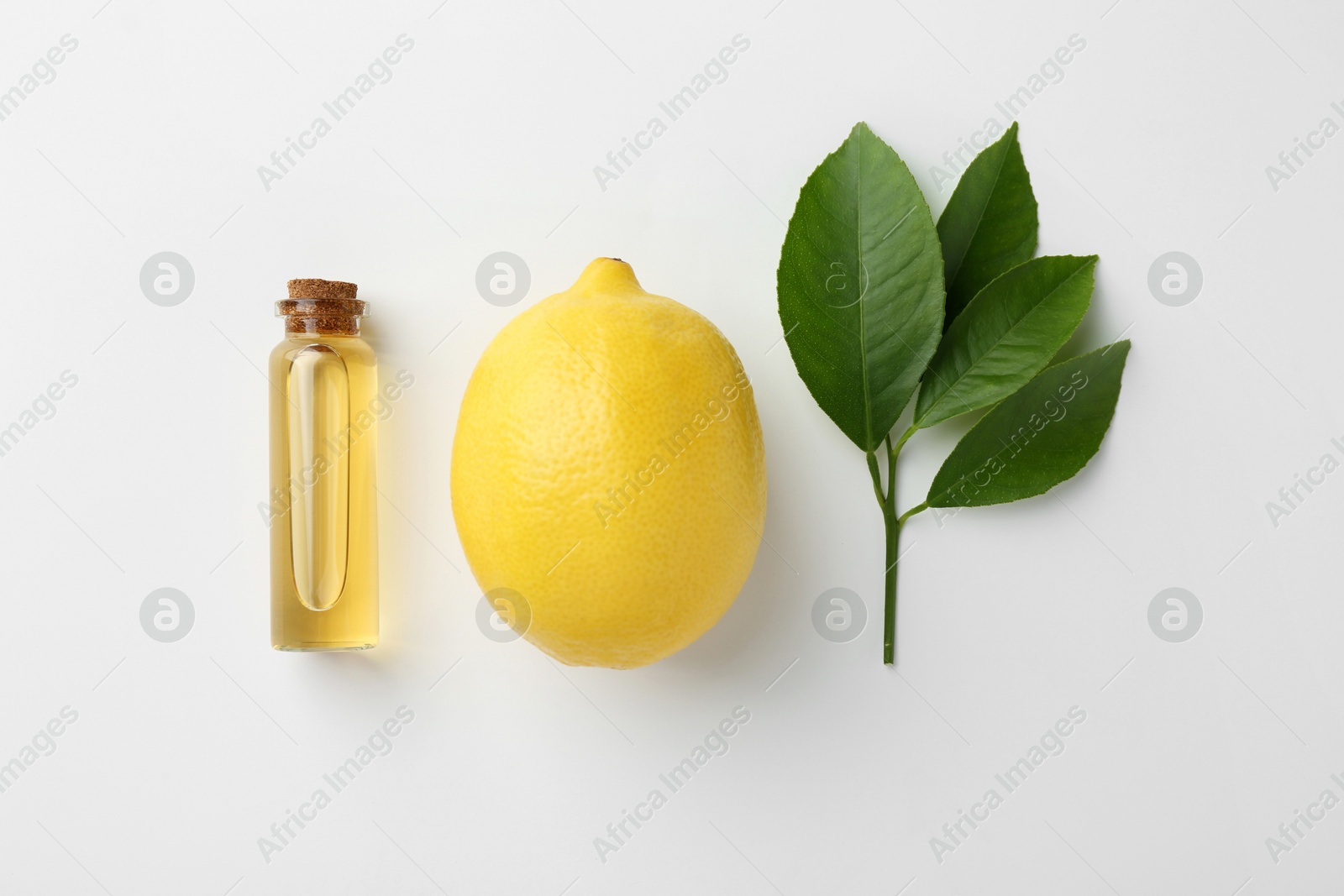 Photo of Bottle of essential oil, lemon and green leaves on white background, flat lay