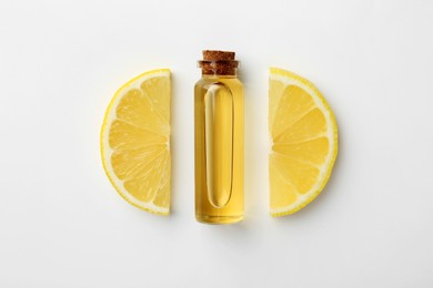 Bottle of essential oil and lemon on white background, top view