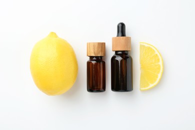 Photo of Bottles of essential oils and lemon on white background, top view