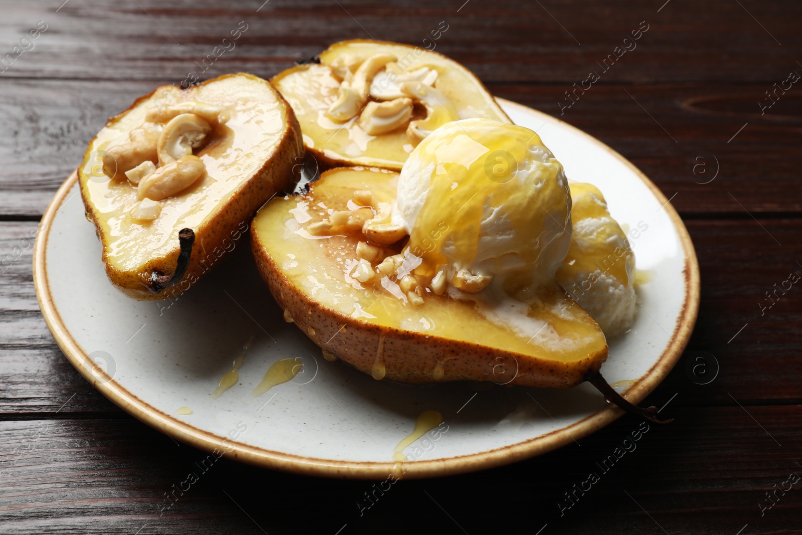 Photo of Delicious baked pears with nuts, ice cream and honey on wooden table, closeup