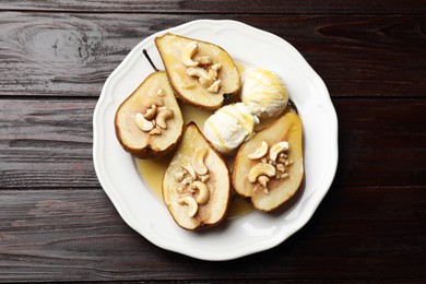 Delicious baked pears with nuts, ice cream and honey on wooden table, top view