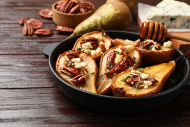 Delicious baked pears with nuts, blue cheese and honey on wooden table, closeup