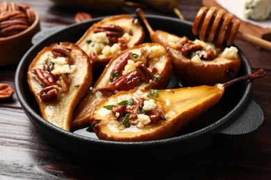 Photo of Delicious baked pears with nuts, blue cheese and honey on wooden table, closeup