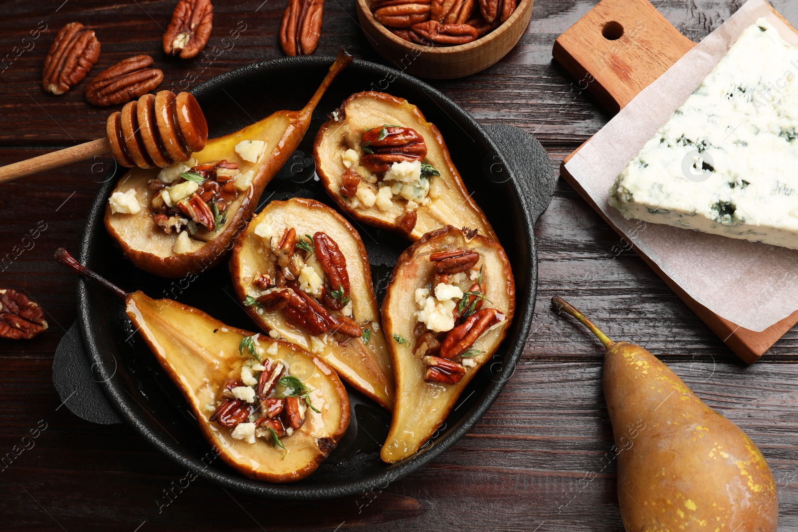 Photo of Delicious baked pears with nuts, blue cheese and honey on wooden table, flat lay