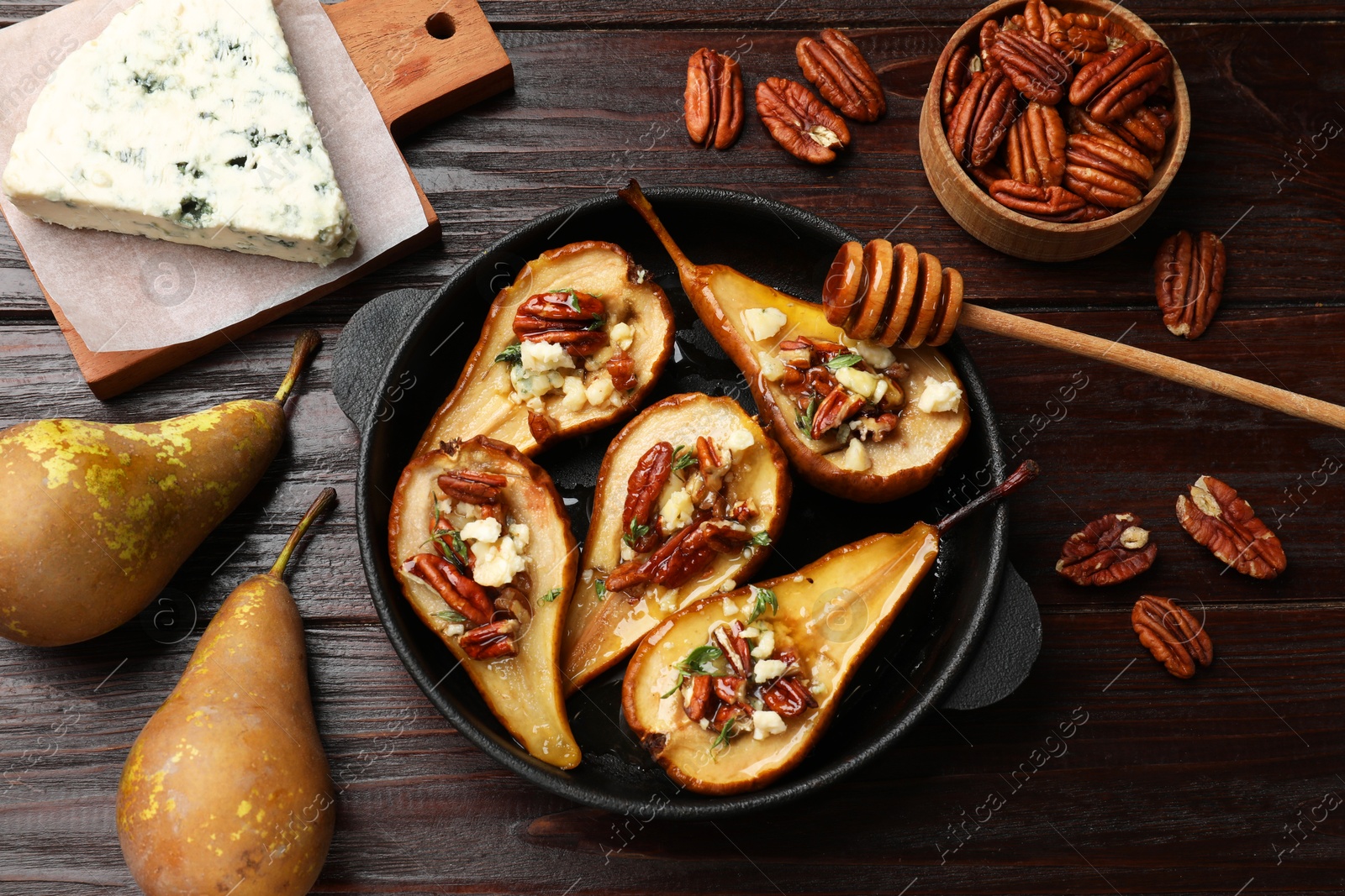 Photo of Delicious baked pears with nuts, blue cheese and honey on wooden table, flat lay