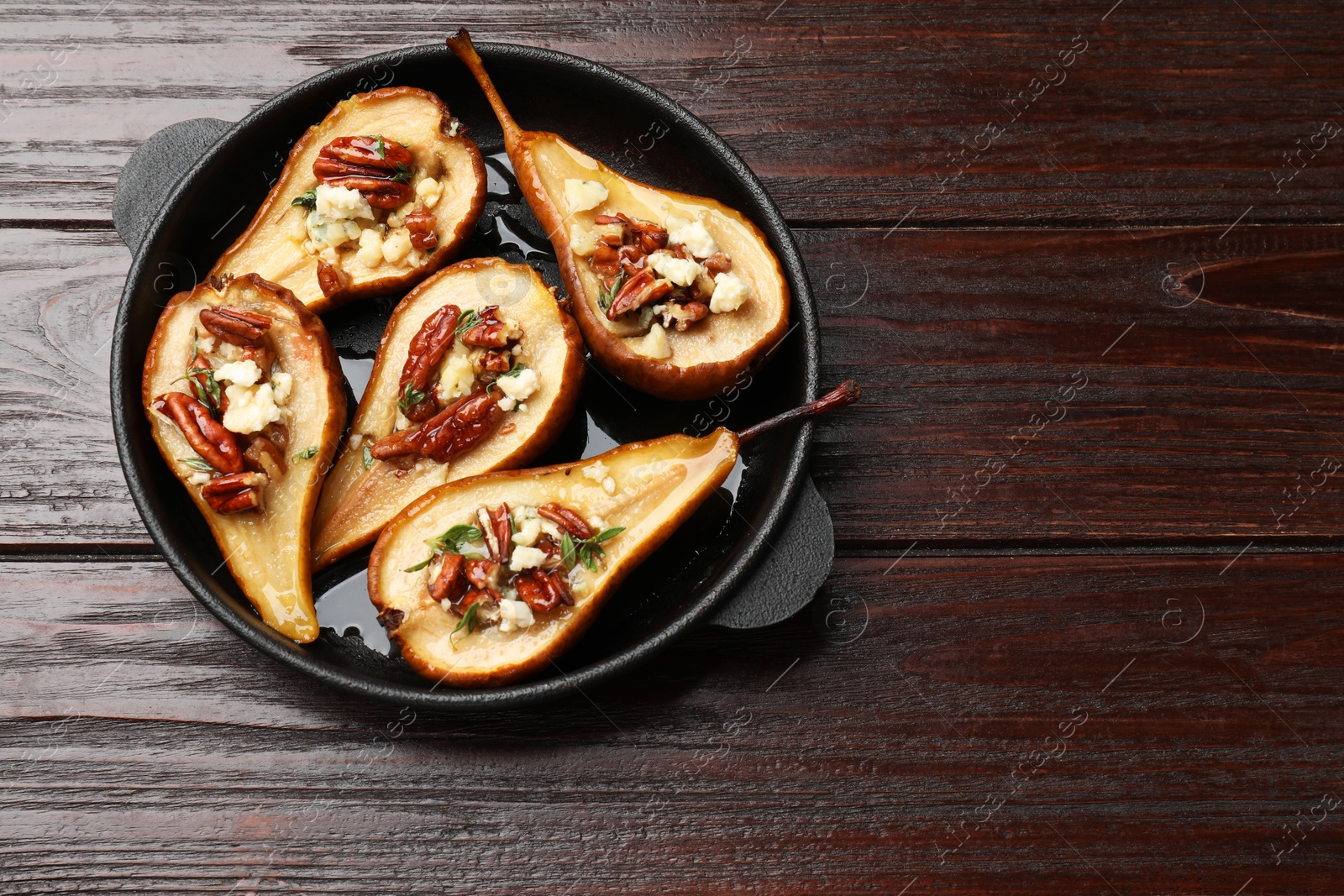 Photo of Delicious baked pears with nuts, blue cheese and honey on wooden table, top view. Space for text