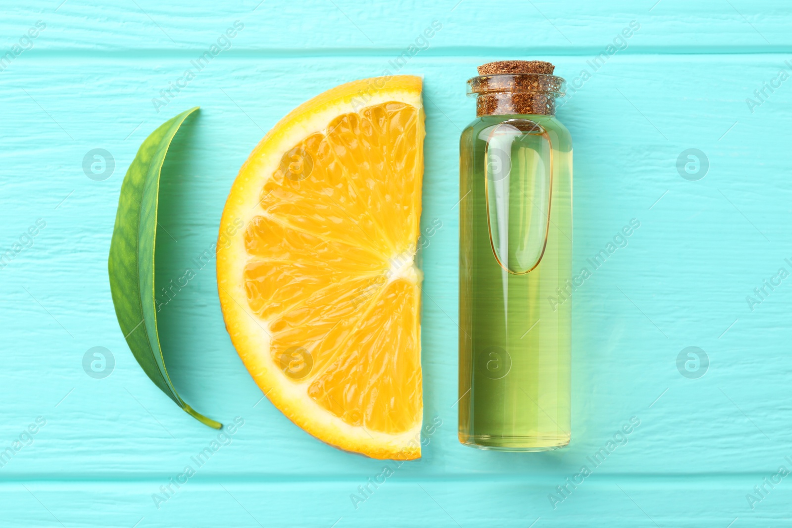 Photo of Bottle of essential oil, orange and green leaf on turquoise wooden table, flat lay