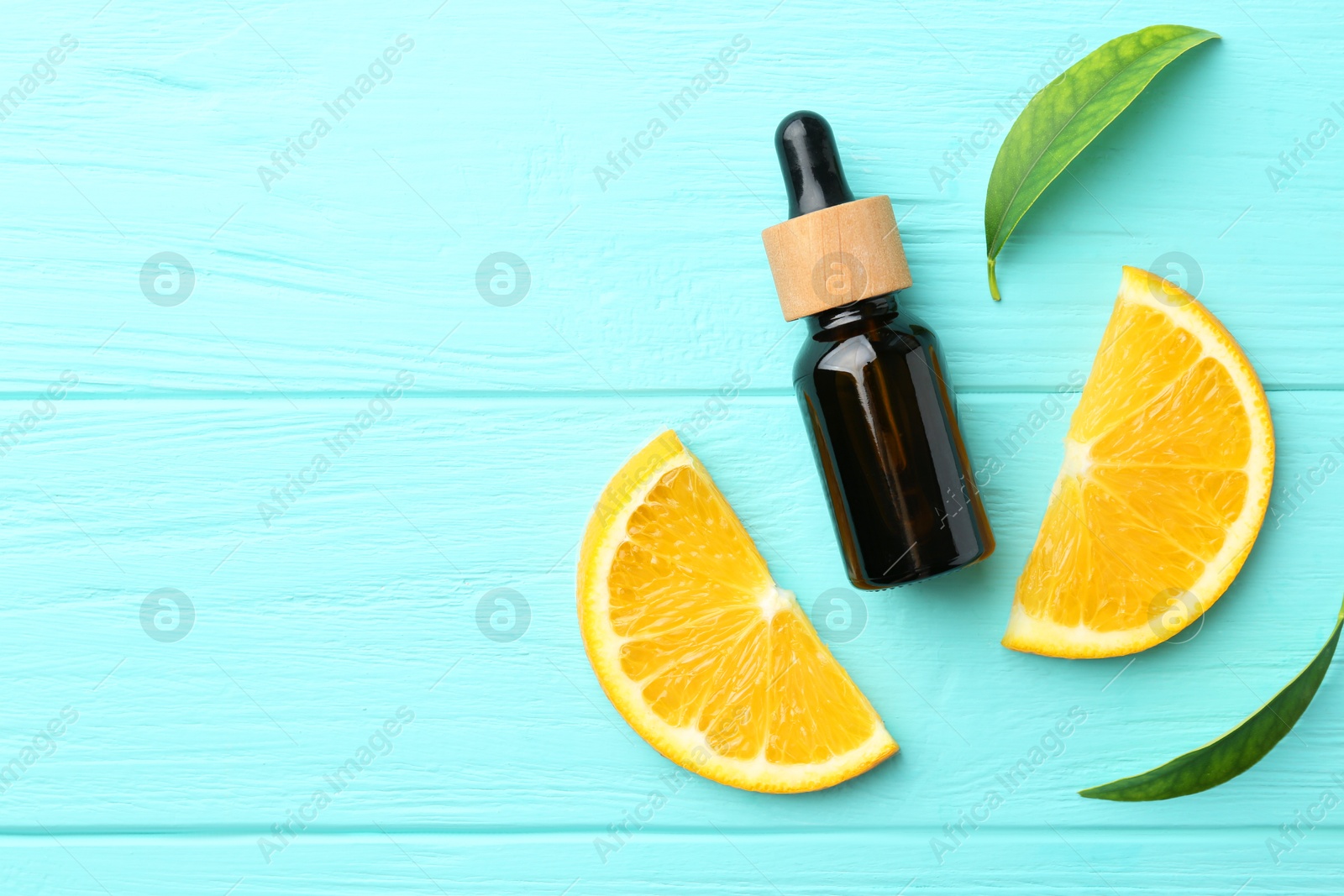 Photo of Bottle of essential oil, orange and green leaves on turquoise wooden table, flat lay. Space for text