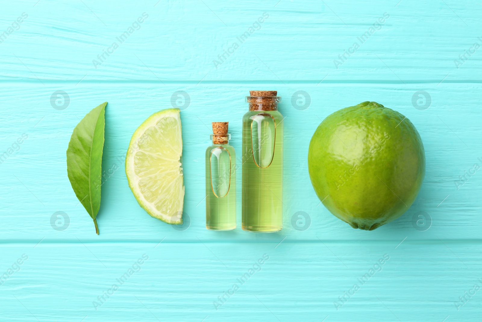 Photo of Bottles of essential oils, lime and green leaf on turquoise wooden table, flat lay