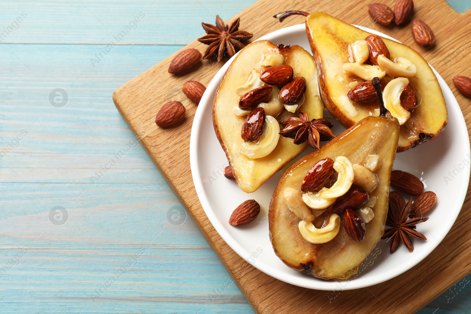 Photo of Delicious baked pears with nuts, anise stars and honey on light blue wooden table, top view. Space for text