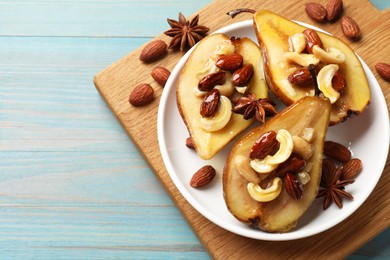 Delicious baked pears with nuts, anise stars and honey on light blue wooden table, top view. Space for text