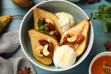 Photo of Delicious baked pears with nuts, ice cream and honey in bowl on light blue wooden table, flat lay