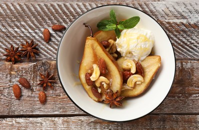 Photo of Delicious baked pears with nuts, ice cream, anise stars and honey in bowl on wooden rustic table, flat lay