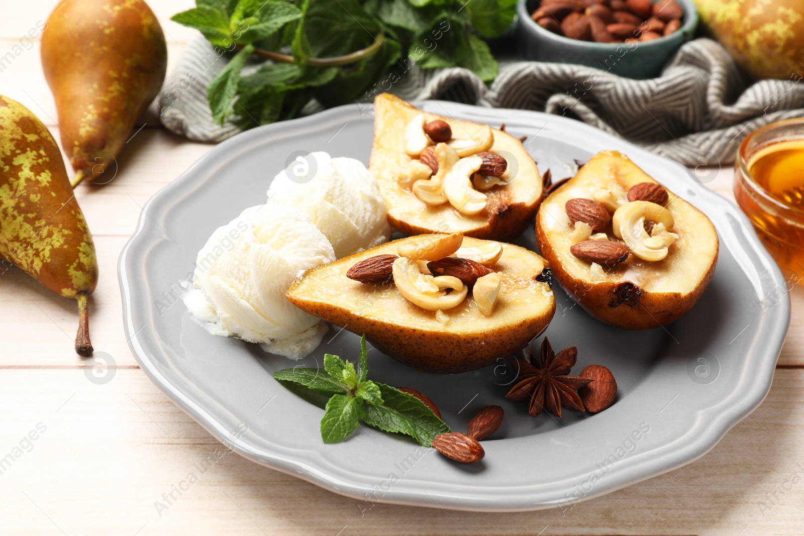 Photo of Delicious baked pears with nuts, ice cream, mint and honey on light wooden table, closeup