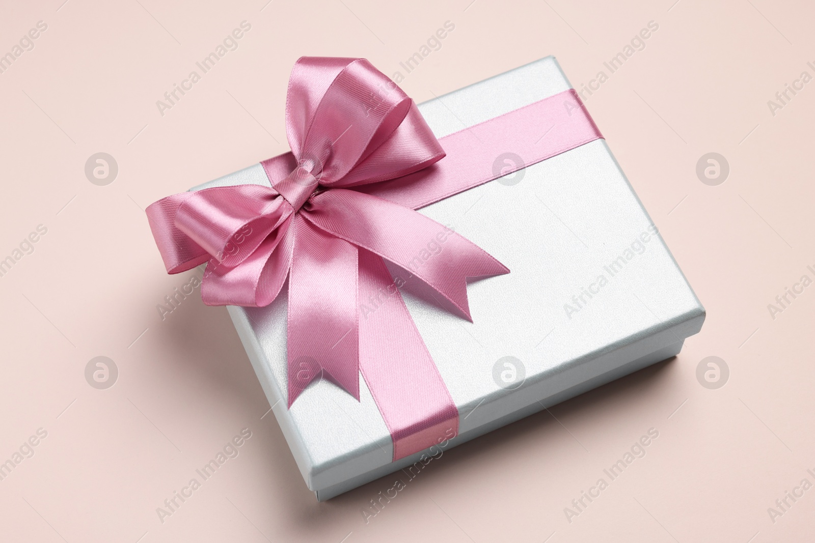 Photo of Beautiful gift box with pink bow on beige background