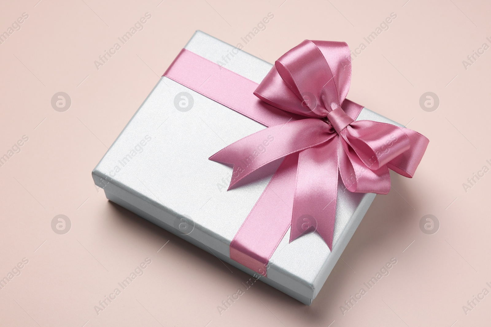 Photo of Beautiful gift box with pink bow on beige background