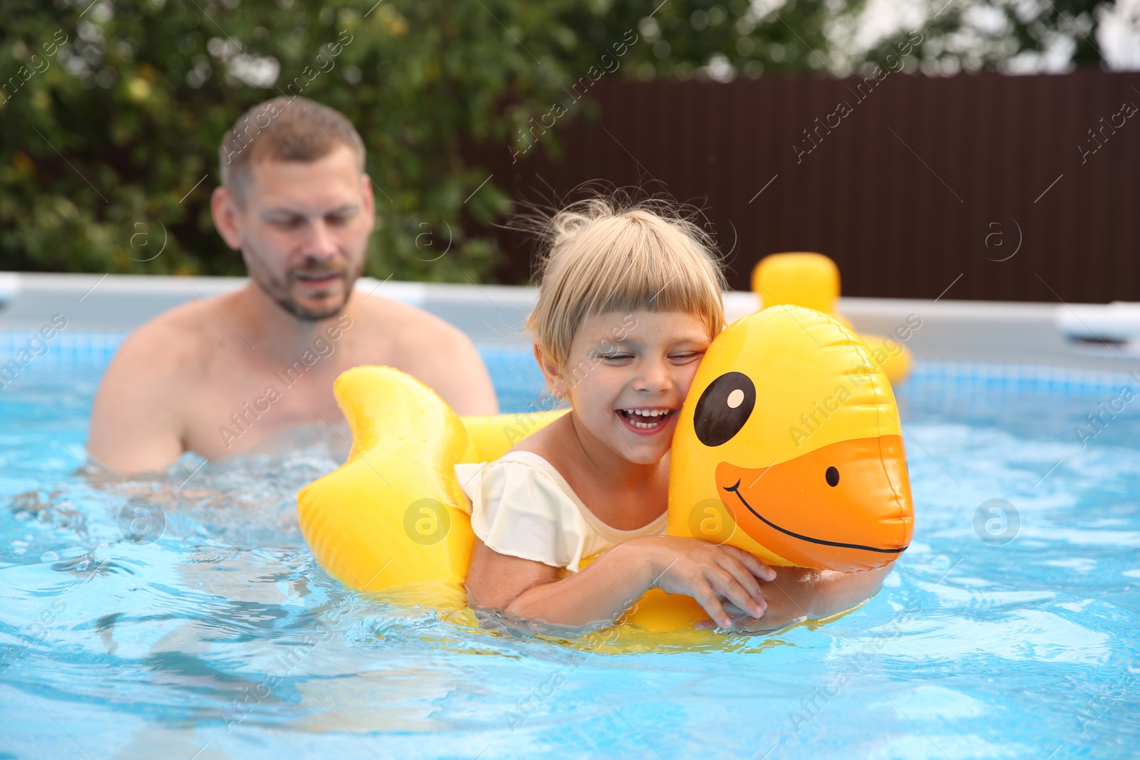 Photo of Happy daughter and her father swimming in pool