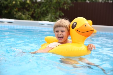 Photo of Happy girl swimming with inflatable ring in pool