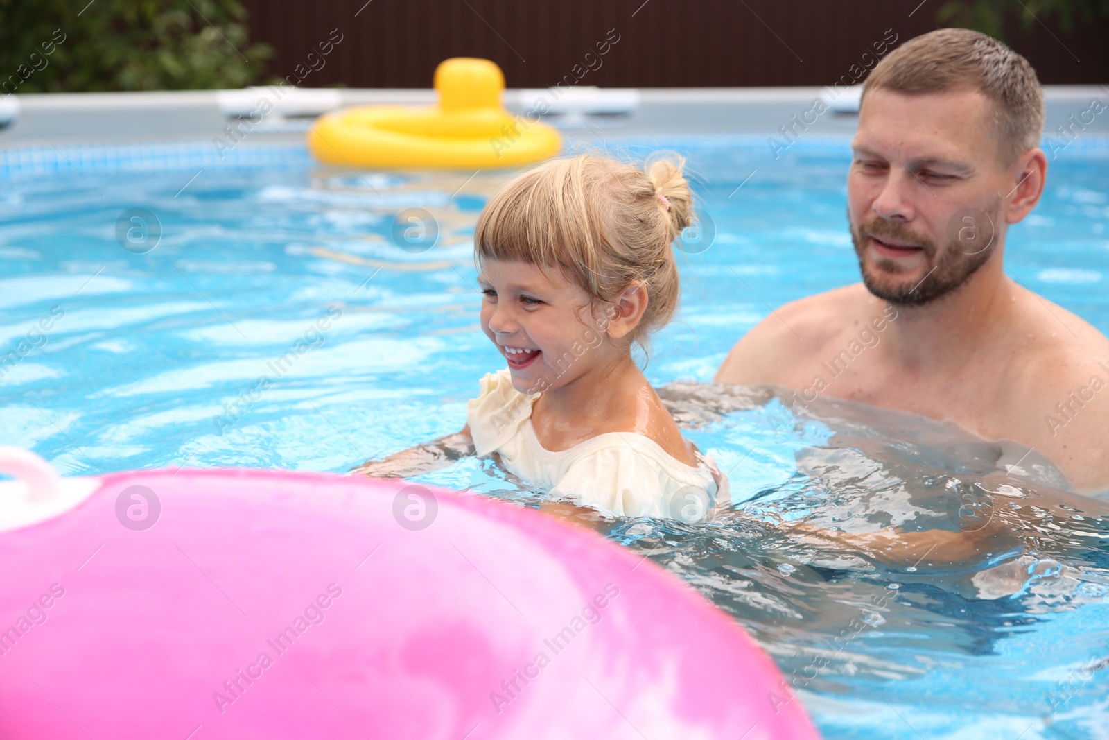 Photo of Happy daughter and her father swimming in pool