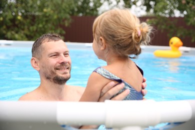 Photo of Happy father having fun with his daughter in swimming pool