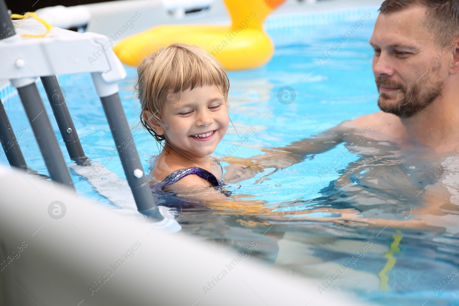 Photo of Happy daughter and her father near ladder in swimming pool