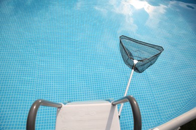 Photo of One skimmer net, ladder and swimming pool, above view