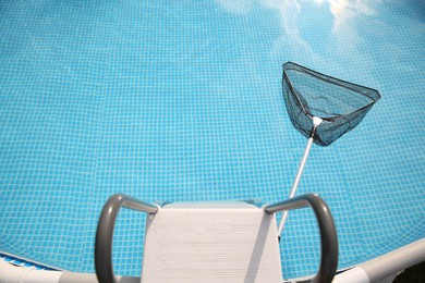 Photo of One skimmer net, ladder and swimming pool, above view