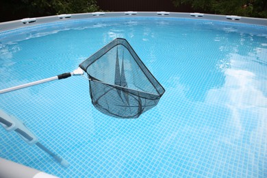 Photo of Cleaning swimming pool with skimmer net, closeup