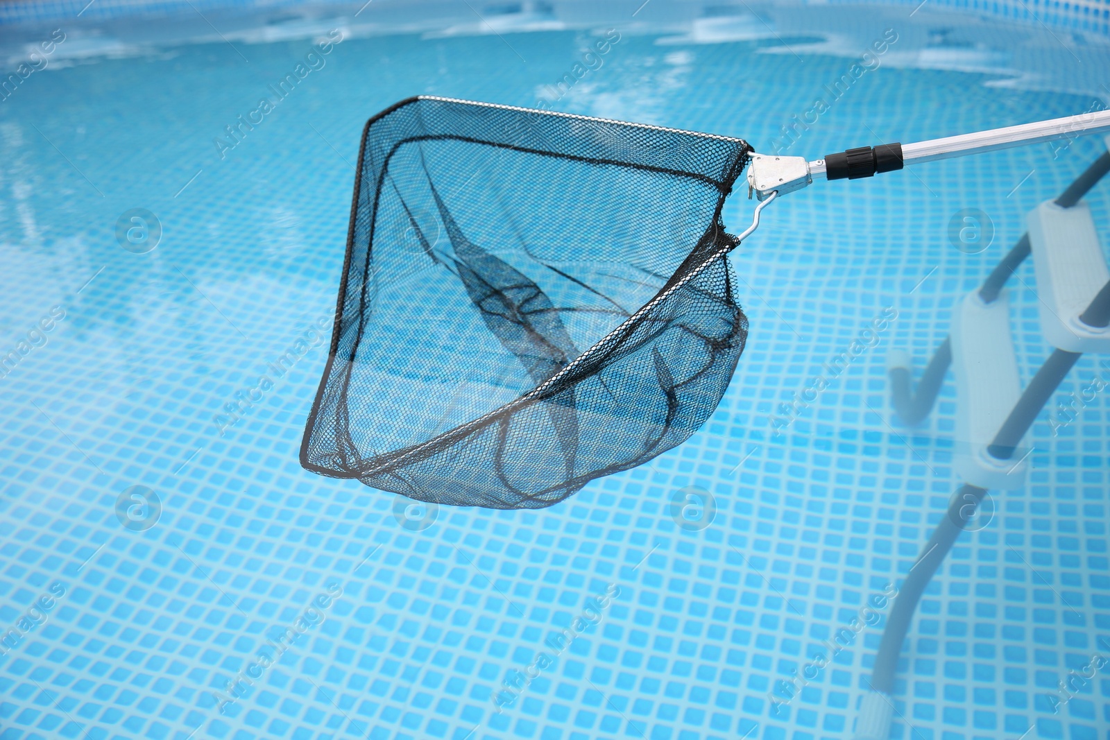 Photo of Cleaning swimming pool with skimmer net, closeup