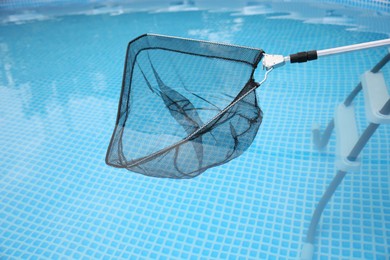 Cleaning swimming pool with skimmer net, closeup