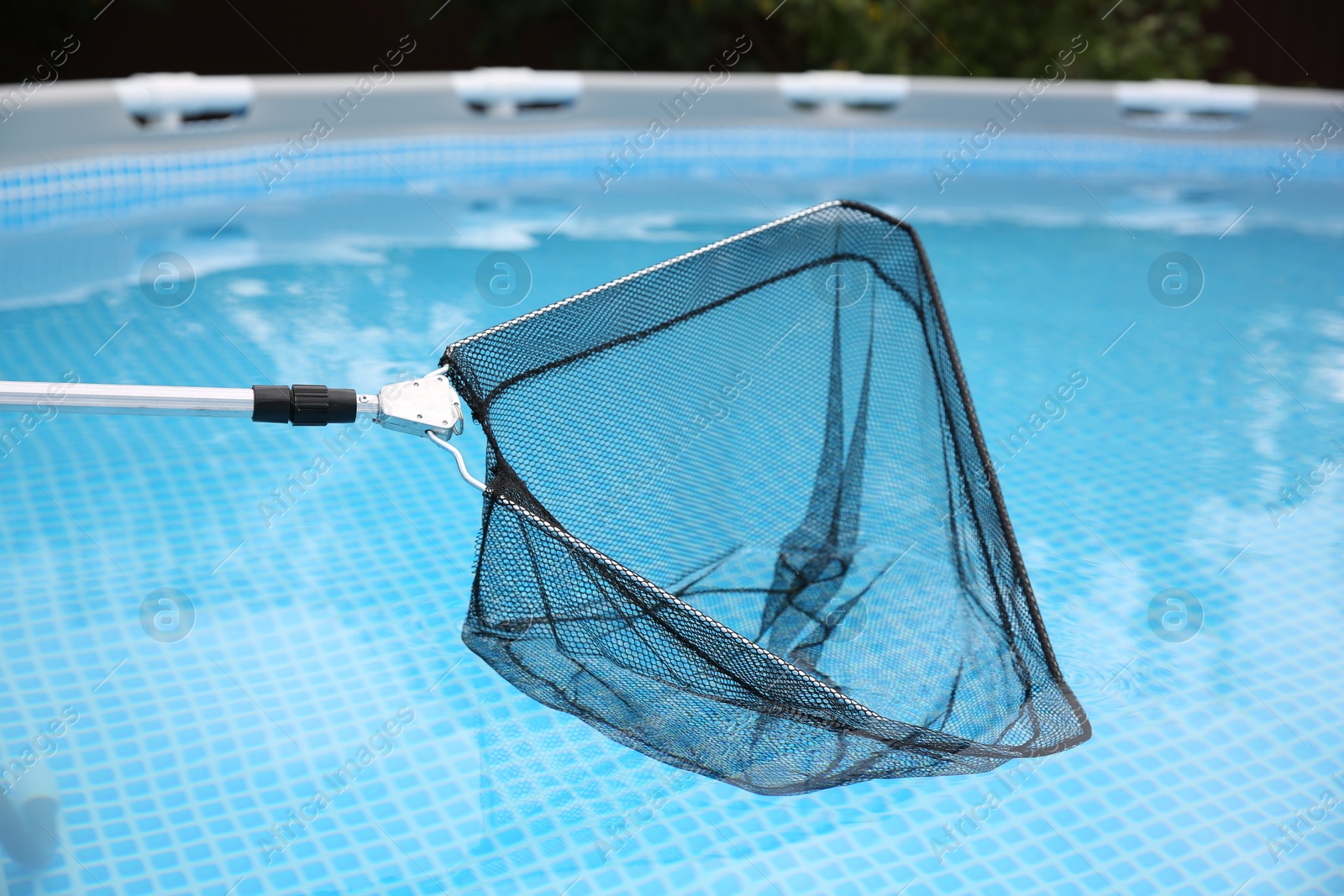 Photo of Cleaning swimming pool with skimmer net, closeup