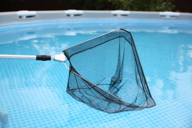 Photo of Cleaning swimming pool with skimmer net, closeup