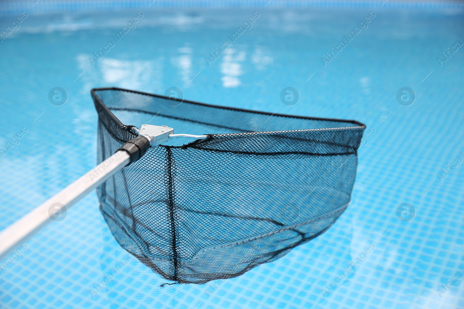 Photo of Cleaning swimming pool with skimmer net, closeup