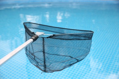 Cleaning swimming pool with skimmer net, closeup