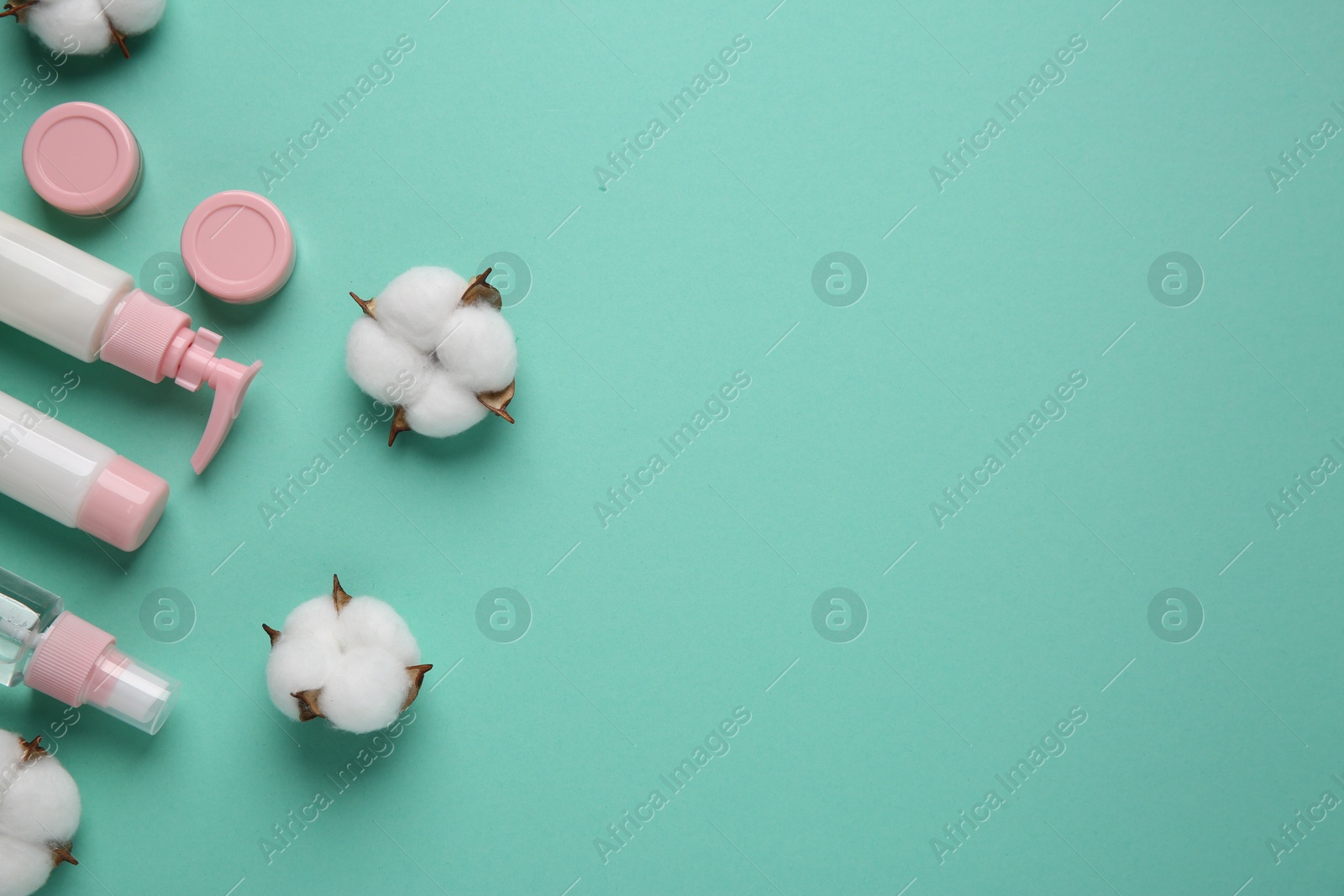 Photo of Different cosmetic products and cotton flowers on turquoise background, flat lay. Space for text