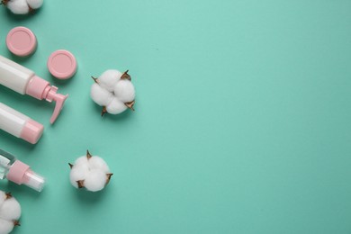 Different cosmetic products and cotton flowers on turquoise background, flat lay. Space for text