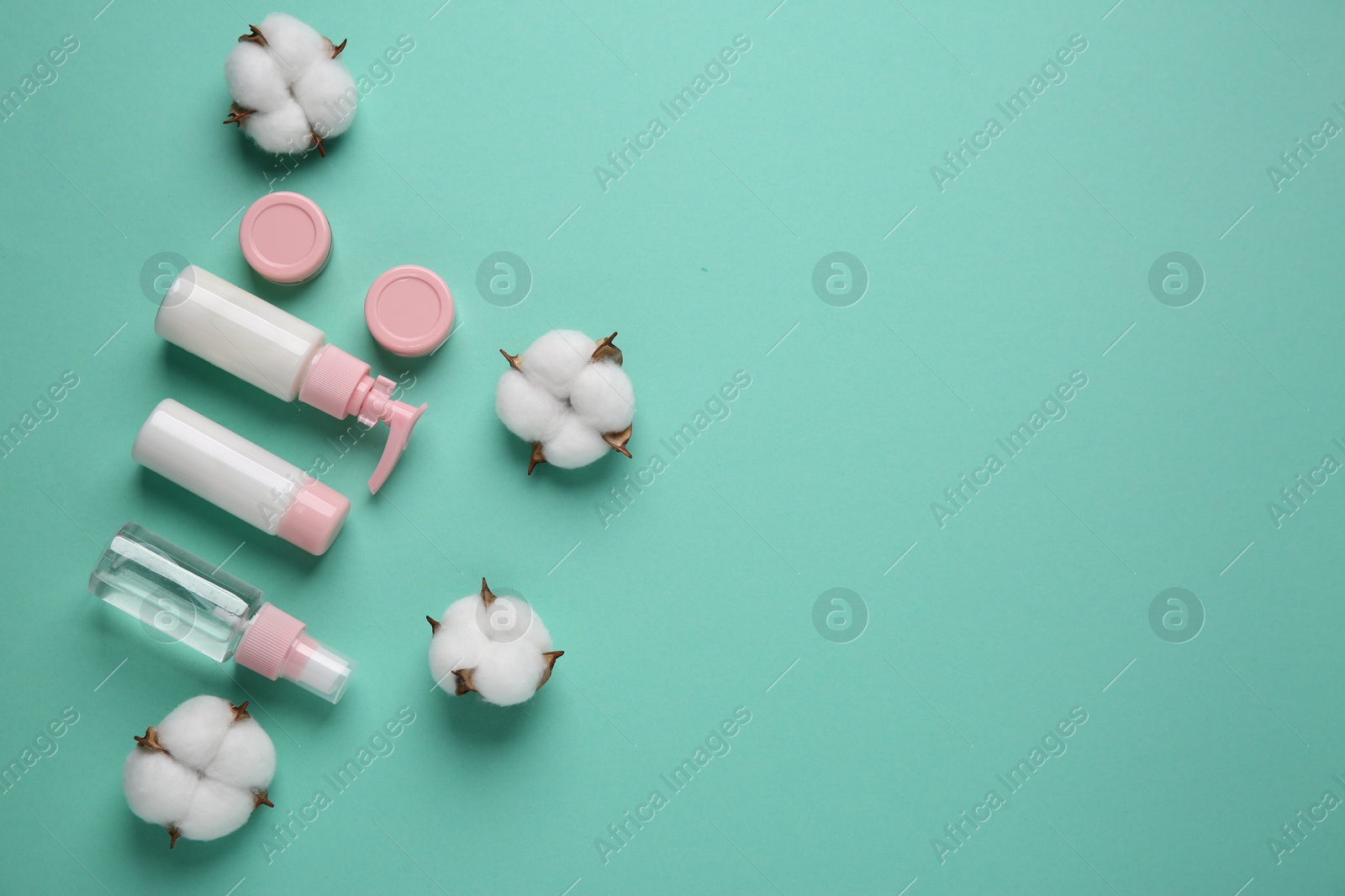 Photo of Different cosmetic products and cotton flowers on turquoise background, flat lay. Space for text