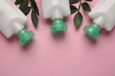 Photo of Different cosmetic products and green leaves on pink background, flat lay. Space for text