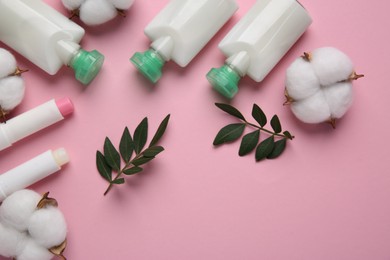 Photo of Different cosmetic products, leaves and cotton flowers on pink background, flat lay. Space for text